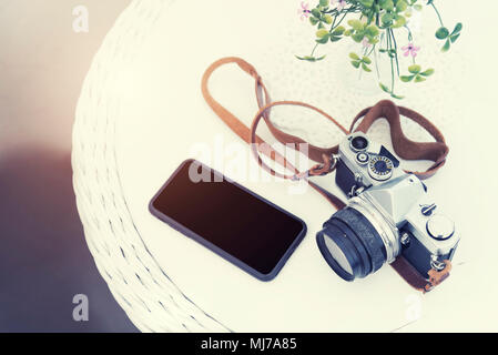 Lifestyle, Reisen und Technik Konzept. Vintage Kamera mit Mobile auf Tabelle mit kostenlose Kopie. Vintage und retro Kulisse. Bild zum Text hinzufügen m Stockfoto