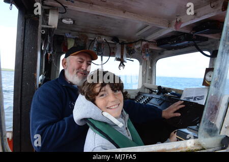 Junge fischen mit seinem Opa in einem Meer boot Makrelenfangs der Küste der Shetlandinseln Stockfoto