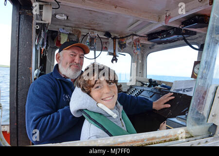 Junge fischen mit seinem Opa in einem Meer boot Makrelenfangs der Küste der Shetlandinseln Stockfoto