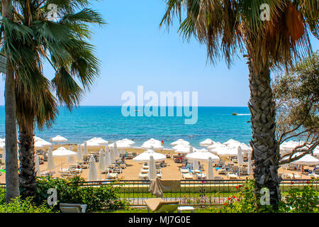 Blick auf den Strand, schöne türkisblaue Meer, Strand mit Liegen und Sonnenschirmen, viele Palmen schöne Aussicht Stockfoto
