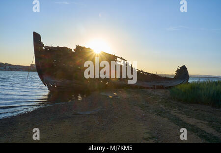 Der Blick auf die Wracks der alten hölzernen Segelboot zerstört und verbrannt auf der Bank der Seixal Bucht des Tejo im Licht der untergehenden Sonne. Lissabon. Portu Stockfoto