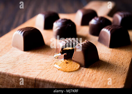 Alkohol fließt aus der Schokolade auf Holz- Oberfläche. Dessert Konzept. Stockfoto