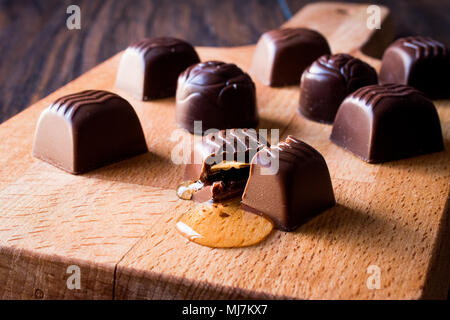 Alkohol fließt aus der Schokolade auf Holz- Oberfläche. Dessert Konzept. Stockfoto