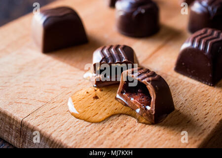 Alkohol fließt aus der Schokolade auf Holz- Oberfläche. Dessert Konzept. Stockfoto