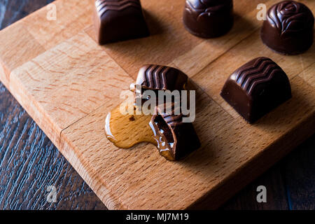 Alkohol fließt aus der Schokolade auf Holz- Oberfläche. Dessert Konzept. Stockfoto