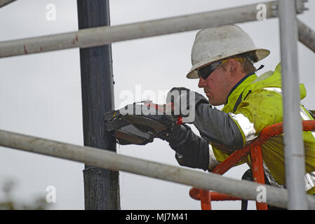 MOANA, NEUSEELAND, November 4, 2017: Ein Ingenieur im Regen Arbeiten verwendet eine kleine bandsäge dem Stahlgehäuse eines Öl gut Wird plugge zu schneiden Stockfoto