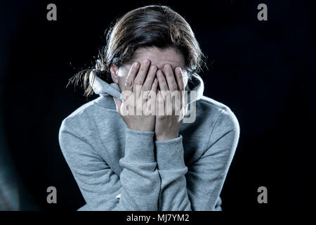 Konzept der Angst, Scham, Gewalt und Depression. Attraktive latin depressiven Frau, die ihr Gesicht mit den Händen auf einem isolierten schwarzen Hintergrund Stockfoto