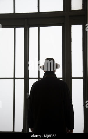 Silhouette der Mann mit Hut aus dem Fenster zu schauen. Stockfoto