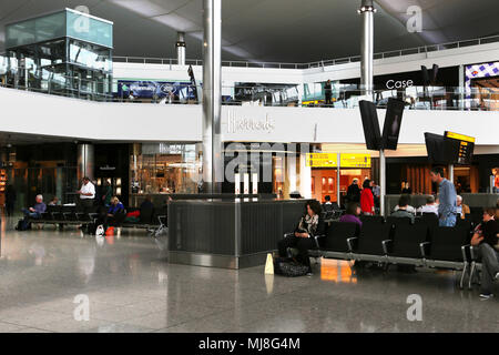 England Heathrow Airport Terminal 2 Passagiere warten auf Flügen in der Abflughalle mit Duty Free Läden Harrods Stockfoto