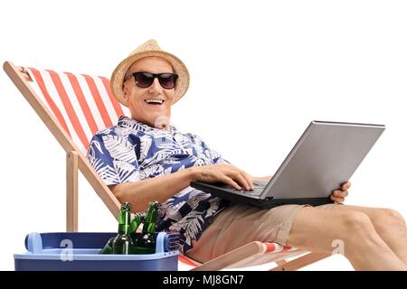 Alte Tourist mit einem Laptop in einem Liegestuhl sitzt neben eine Kühlbox, und wenn man die Kamera auf weißem Hintergrund Stockfoto
