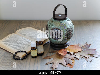 Die ultraschall Aroma-diffusor ist in Form eines alten Lampe gemacht. Aromatische Diffusor ist auf dem Holztisch. Es sind die ätherischen Öle, Buch, trockene leav Stockfoto