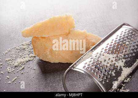 Parmesan gerieben und ganze mit Reibe auf grauem Hintergrund. Stockfoto
