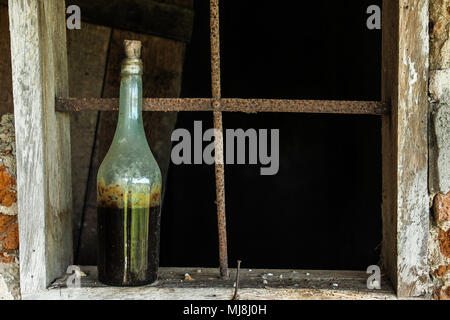 Alte Flasche sitzt auf einem alten Fensterrahmen Stockfoto