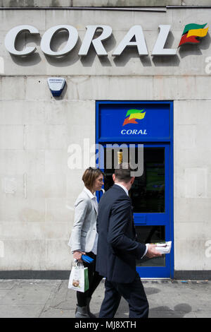 Ein paar außerhalb der hinteren Eingang des Coral Wettbüro auf Warren Street, London, NW1, UK Stockfoto