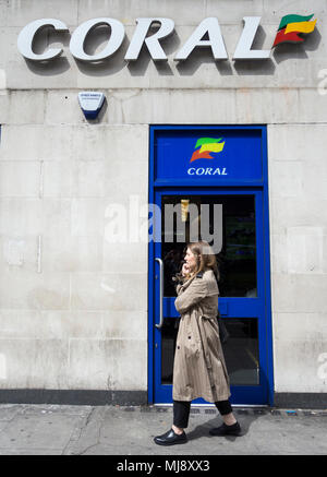 Eine Frau außerhalb der hinteren Eingang des Coral Wettbüro auf Warren Street, London, NW1, England warten Stockfoto