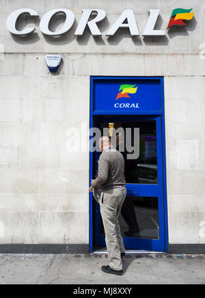 Ein Mann, der durch den hinteren Eingang des Coral Wettbüro auf Warren Street, London, NW1, UK Stockfoto