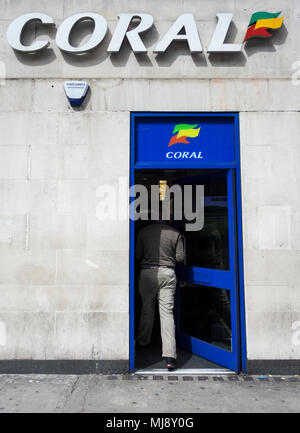 Ein Mann, der durch den hinteren Eingang des Coral Wettbüro auf Warren Street, London, NW1, UK Stockfoto