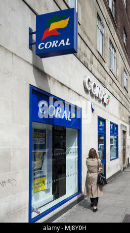 Eine Frau außerhalb der hinteren Eingang des Coral Wettbüro auf Warren Street, London, NW1, England warten Stockfoto