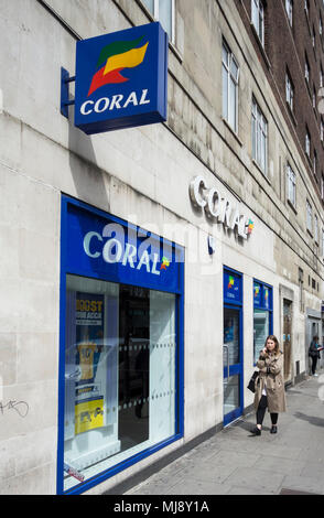 Eine Frau außerhalb der hinteren Eingang des Coral Wettbüro auf Warren Street, London, NW1, England warten Stockfoto