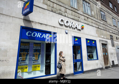 Eine Frau außerhalb der hinteren Eingang des Coral Wettbüro auf Warren Street, London, NW1, England warten Stockfoto