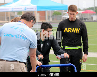 Kapitän Michael Havro mit den 211 Mobile Public Affairs Distanz, in der Bryan Texas stationiert, Escorts einer der Athleten zu ihrer Startposition während der Special Olympics Texas Frühling Spiele in College Station, Texas, 21. April 2018. Special Olympics Texas ist Teil der Special Olympics ist die weltweit größte Sportorganisation für Kinder und Erwachsene mit Behinderungen, bietet das ganze Jahr über lokale und regionale Wettbewerbe. (Armee Foto von Sgt. Rigo Cisneros/Freigegeben) Stockfoto