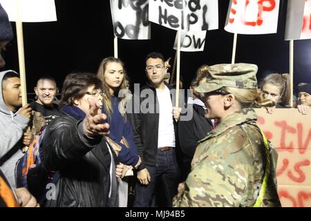 Vertriebene zivilen Akteuren inszeniert ein mock Protest, viele halten Schilder anspruchsvolle Nahrung, Wasser und Medizin. 1. Sgt. Smilla Fiorucci von der 864th Engineer Battalion (Herzschrittmacher), Joint Base Lewis-McChord, W. A., sprach mit der Masse, wie sie ihre Sorge um ihr in Responder Support Camp Jennings, Ind, während Wächter Antwort 18. Am 24. April 2018 zum Ausdruck gebracht. Mehr als 4.500 Soldaten aus dem ganzen Land beteiligen sich an Wächter Antwort 18, a multi-component Training übung für die Fähigkeit der US-Armee Einheiten" die Verteidigung Unterstützung der zivilen Behörden (D zu unterstützen validieren Stockfoto