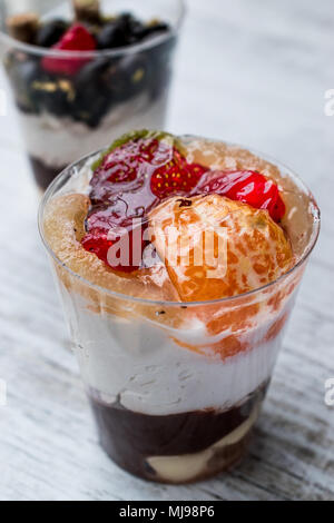 Früchte und Schokolade Chips Parfait mit Joghurt im Glas Schale auf weißem Holz- Oberfläche Stockfoto