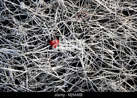 Ein rotes Glas Herz in der Mitte von einem Gewirr von Karte Reste auf einem Hintergrund von Schiefer. Stockfoto