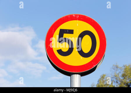 Schild auf Pole Höchstgeschwindigkeit 50 mit schwarzen Ziffern ob-gelben Hintergrund und rotem Rand am blauen Himmel. Stockfoto