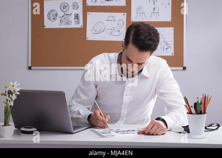 Junge männliche Künstler Skizzieren auf weißes Papier über Schreibtisch Stockfoto