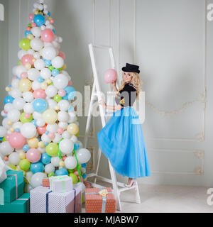 Nette und schöne Blondine in einem fabelhaften Inneren. Charmante junge Frau in einer geschwungenen blauen Rock. Ungewöhnliche Weihnachten Stil Stockfoto