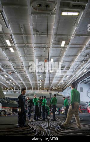 180424-N-EG 099-090 PAZIFISCHEN OZEAN (24. April 2018) Segler Guide einem Festhaltenen gang Draht durch den Overhead des Hangar Bay an Bord der Flugzeugträger USS John C Stennis (CVN 74). John C Stennis ist im Gange, Durchführung von Schulungen zur Vorbereitung der nächsten geplanten Bereitstellung. (U.S. Marine Foto von Mass Communication Specialist 2. Klasse Charles D. Gaddis IV/Freigegeben) Stockfoto