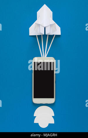 Starten oder schnelle Verbindung Konzept. Die Einführung Papier Rakete mit Smart Phone auf blauen Himmel mit Wolken. Origami. Papier schneiden. Ansicht von oben Stockfoto