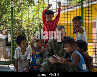 Us Navy Lieutenant Cmdr. Robert Nelson schaut auf sein Handy während einer Kooperative Gesundheit Engagement bei Sto Nino in Baguio City, Philippinen, zur Unterstützung der Übung Balikatan, 25. April 2018. Nelson ist der Kaplan des 1. Marine Flugzeugflügel, und ist eine 49-jährige gebürtige von Mesa, Arizona. Balikatan 34-2018, in seiner 34. Iteration, ist eine jährliche US-Philippinischen militärische Ausbildung Übung auf einer Vielzahl von Missionen, einschließlich humanitärer Hilfe und Katastrophenhilfe, Terrorismusbekämpfung und andere kombinierte militärische Operationen von Mai 7. bis 18. (U.S. Marine Corps Foto von Sgt. Matthew J. Bragg) Stockfoto