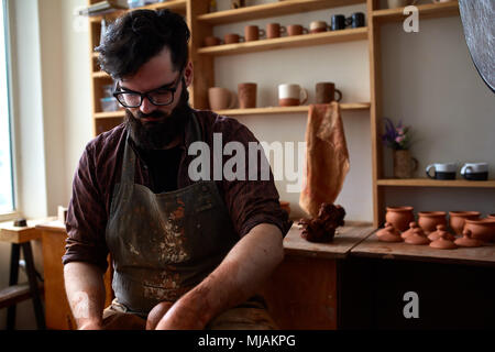 Porträt einer stattlichen bärtigen Mann Töpfer in Plaid Shirt und schmutzigen Schürze Arbeiten in seinem Atelier, selektiver Fokus, Nahaufnahme. Kreative Arbeit. Cra Stockfoto