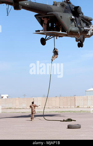 Eine irakische Terrorismusbekämpfung Service Student schnell - Seile aus einem Hubschrauber, während seine Ausbilder Uhren aus der Masse an Bagdad, 25. April 2018. Die fast-rope Training ist darauf ausgelegt, die Fähigkeit des Irak CTS-Operationen mit ihren eigenen Luftwerte Verhalten zu verbessern. CTS sind das Fundament für die Zukunft des Irak durch die Verbesserung ihrer Fähigkeiten, um ein sicheres und stabiles Umfeld für ihre Nation zu stellen. (U.S. Armee Foto von Sgt. William A. Parsons) Stockfoto