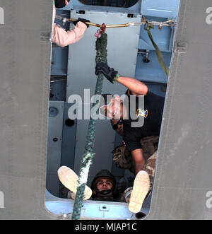 Eine irakische Terrorismusbekämpfung Service Student (unten) zu schnell bereitet - Seil von einem schwebenden Hubschrauber während seinem Ausbilder (rechts) in Bagdad, April 25, 2018 schaut. Die fast-rope Training ist darauf ausgelegt, die Fähigkeit des Irak CTS-Operationen mit ihren eigenen Luftwerte Verhalten zu verbessern. CTS sind das Fundament für die Zukunft des Irak durch die Verbesserung ihrer Fähigkeiten, um ein sicheres und stabiles Umfeld für ihre Nation zu stellen. (U.S. Armee Foto von Sgt. William A. Parsons) Stockfoto