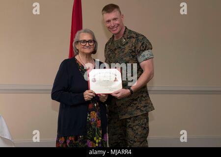 Colonel Russell Burton, Links, kommandierender Offizier, Marine Corps Air Station New River, stellt eine Auszeichnung für Christine Rogers während der Präsidentschaftswahlen Auszeichnungen und freiwillige Anerkennung Zeremonie auf der Marine Corps Air Station New River, N.C., 26. April 2018. Der Zweck dieser Zeremonie wurde zu Ehren Marines und Familienangehörigen für Ihre umfangreiche Community Service von 100 Stunden oder mehr. (U.S. Marine Corps Foto von Lance Cpl. Ursula V. Smith) Stockfoto