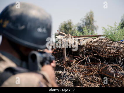 Südwesten Asien - Ein irakischer Terrorismusbekämpfung student Spots eine simulierte Improvised Explosive Device inmitten der Trümmer außerhalb der fiktiven Dorf Medina, Bagdad, 30. April 2018. Die Ausbildung in Medina Dorf wurde durch die Streitkräfte der Koalition zu helfen, CTS-Studenten ihre Kampftechniken wie Close Quarters Combat bauen, Identifizierung von IEDs, Einrichten Fahrzeug Checkpoints und der Reaktion auf IED Angriffe. Streitkräfte der Koalition weiterhin die Menschen im Irak zu unterstützen, um die Fähigkeiten der Nation und zur Verbesserung der Sicherheit und Stabilität zu gewährleisten. (U.S. Armee Foto von Sgt. William A. Parsons) Stockfoto