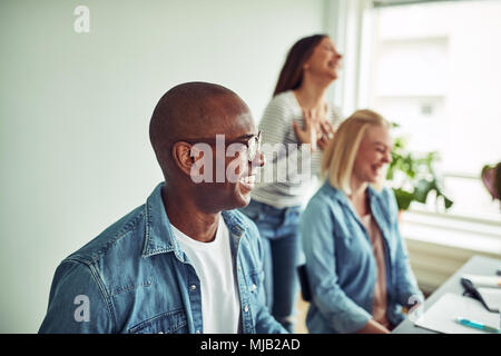 Junge afrikanische Unternehmer mit Kollegen während einer Sitzung gemeinsam lachen in einem modernen Büro Stockfoto