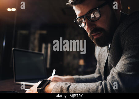 Close-up Portrait von bärtigen Geschäftsmann in Gläsern bei Nacht loft Büro. Kreative manager Arbeiten am späten Abend über einen neuen Anlauf in Coworking studio Stockfoto