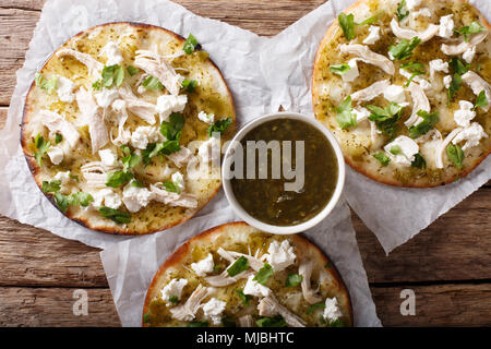 Mexikanischen fast food: frittierte Tortilla mit Hähnchen, Käse und grüne Soße close-up auf dem Tisch. horizontal oben Ansicht von oben Stockfoto