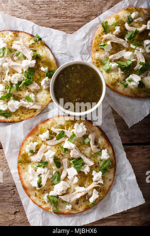 Mexikanischen fast food: frittierte Tortilla mit Hähnchen, Käse und grüne Soße close-up auf den Tisch. Vertikal oben Ansicht von oben Stockfoto