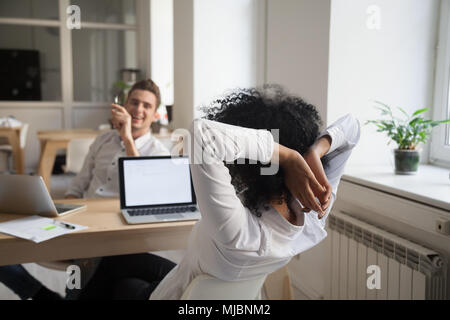 Vielfältigen afrikanischen und kaukasischen Kollegen entspannen im Lachen werden Stockfoto