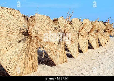 Sonnenschirme in Schilf für Touristen am Strand Stockfoto