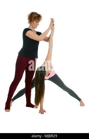 Yoga Lehrerin zeigt, wie ein junges Mädchen in der Yoga position Wide-Legged nach vorne beugen auf Sanskrit Prasarita Padottanasana Variation mit Twist zu setzen Stockfoto