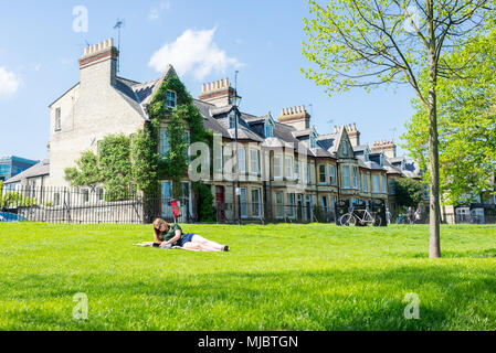 Junge Frau, Student, ein Buch zu lesen, die auf dem Gras genießen das warme Wetter im Frühling in Jesus Green Park, Cambridge, UK. Stockfoto