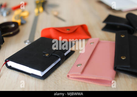 Schwarz und Rosa handgefertigte Leder modische Portemonnaies und Notebook liegen auf dem Tisch. Stockfoto