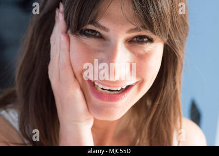 Nahaufnahme Portrait der kaukasischen junge Frau mit dunklen langen Haaren und Bangs. lächelnd, überrascht, Ausdruck. Stockfoto