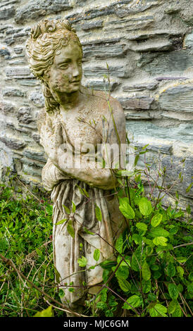 Garten Ornamente wie griechische Statuen langsam von Efeu und Clematis wächst in der Frühlingssonne überwuchert wird. Stockfoto